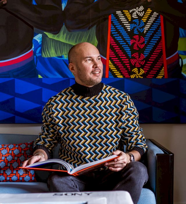 Olivier Chow sitting in front of a painting (partial) by Marc Padeu. Photo: Sacha Di Poi. Courtesy of Olivier Chow